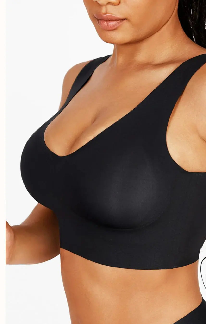 Black seamless shapewear crop top with wide straps and supportive fit, modeled on a woman against a white background.